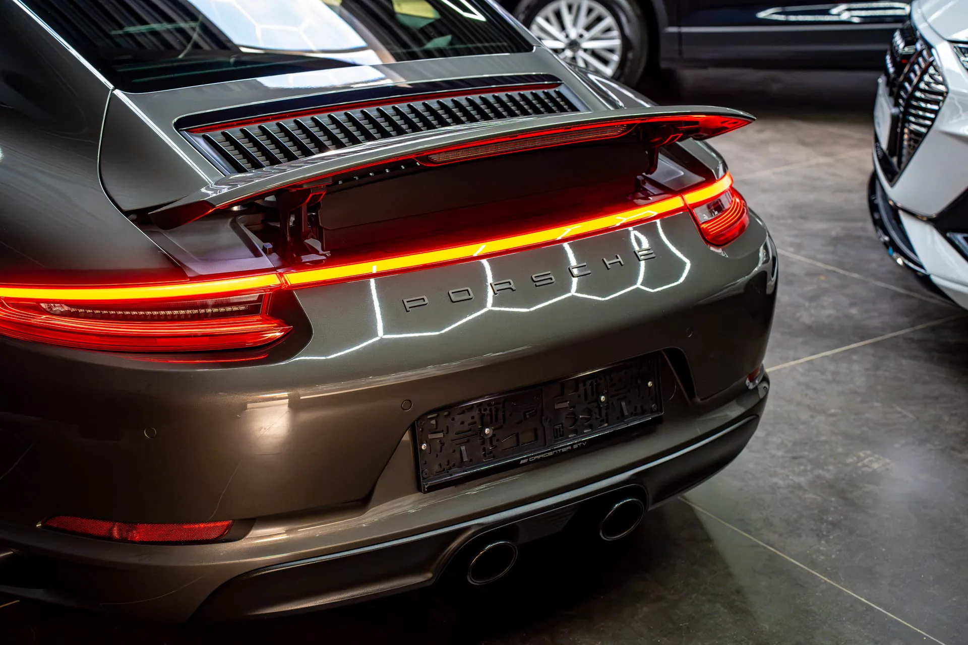 Porsche 911 met verlichte achterlichten in de showroom van Carcenter STV Menen
